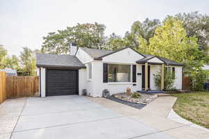 View of front facade featuring brick siding, a garage, driveway, roof with shingles, and a chimney