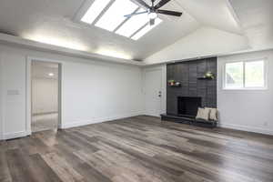 Unfurnished living room featuring ceiling fan, a brick fireplace, and dark wood-type flooring