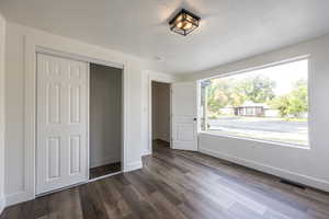 Unfurnished bedroom with a closet, a textured ceiling, and dark wood finished floors