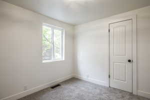 Unfurnished room with baseboards and light colored carpet