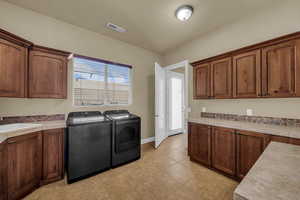 Laundry room featuring cabinet space, independent washer and dryer, and light tile patterned floors