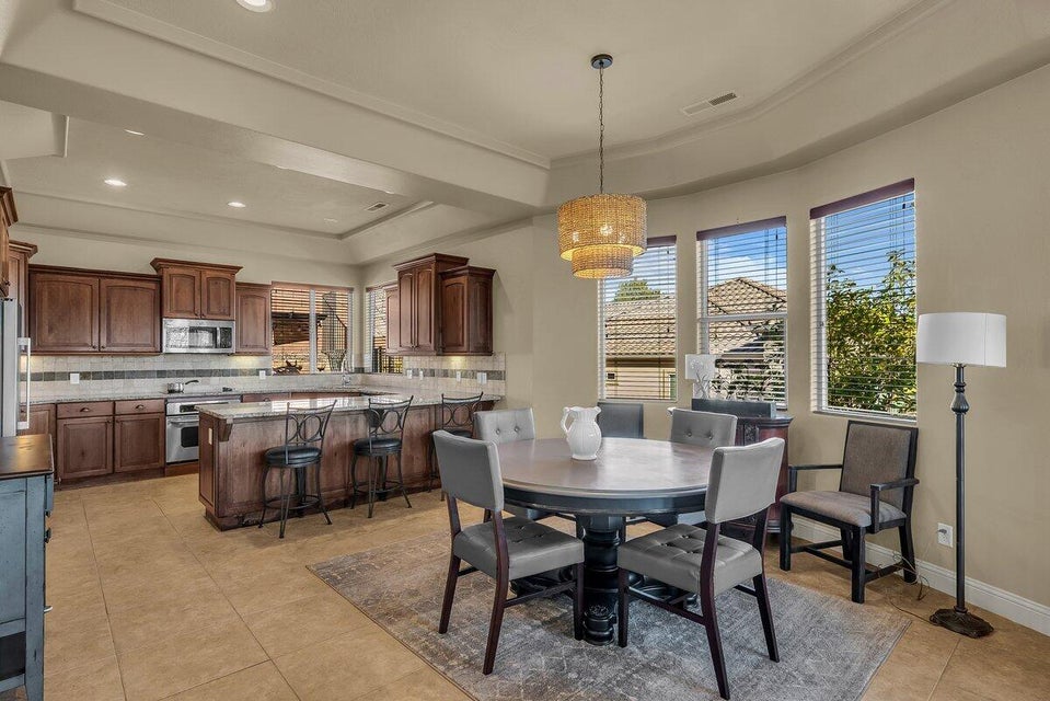 Dining space featuring a raised ceiling, plenty of natural light, light tile patterned flooring, and crown molding