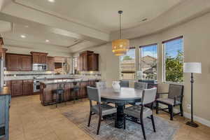 Dining space featuring a raised ceiling, plenty of natural light, light tile patterned flooring, and crown molding