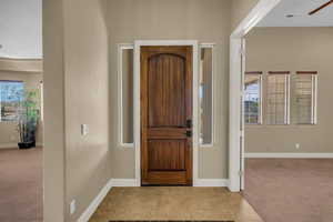 Foyer entrance with light carpet, light tile patterned flooring, and a ceiling fan