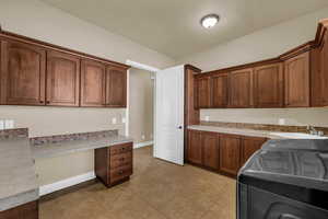 Kitchen featuring built in desk, light countertops, light tile patterned floors, and wood finish cabinets