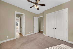 Unfurnished bedroom featuring light carpet, ceiling fan, and a closet