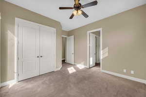 Unfurnished bedroom with light colored carpet, a closet, and a ceiling fan