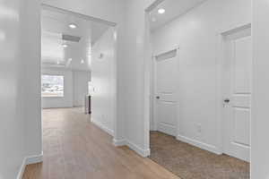 Hallway with light wood-style flooring and recessed lighting