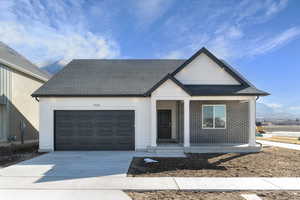 View of front of house with a porch, an attached garage, roof with shingles, driveway, and brick siding