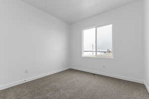 Unfurnished room featuring baseboards and dark carpet