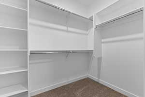 Walk in closet featuring dark colored carpet