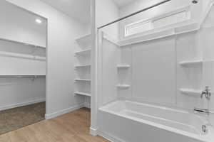 Bathroom with light wood finished floors, a spacious closet, and shower / tub combination