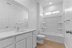 Bathroom with vanity, light wood-style floors, tub / shower combination, and recessed lighting