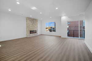 Unfurnished living room with dark wood finished floors, a stone fireplace, and recessed lighting