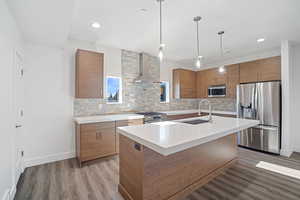 Kitchen featuring wood finish cabinetry, stainless steel appliances, modern cabinets, an island with sink, and dark wood-style floors