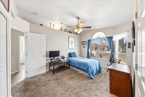 Carpeted bedroom with a ceiling fan and baseboards