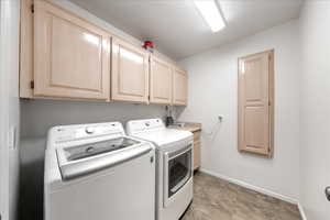 Laundry room featuring separate washer and dryer, stone finish floors, and cabinet space