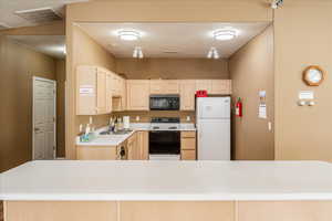 Kitchen featuring light wood finish cabinets, light countertops, and white appliances