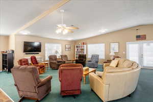 Living room with plenty of natural light, a ceiling fan, carpet floors, and lofted ceiling