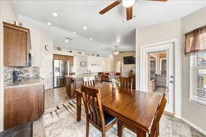 Dining space featuring stone tile floors, a ceiling fan, and vaulted ceiling