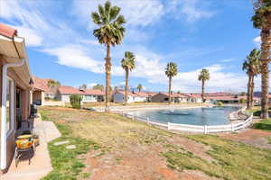 View of pool featuring a water view, a residential view, patio surround, and a lawn