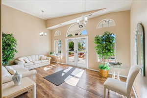 Living area featuring a chandelier, french doors, wood finished floors, and vaulted ceiling