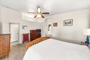 Bedroom featuring carpet, a ceiling fan, and arched walkways