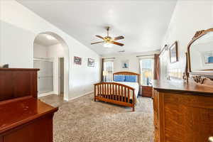 Bedroom with light colored carpet, a ceiling fan, and arched walkways