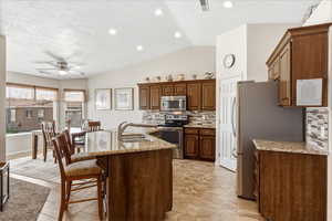 Kitchen with a ceiling fan, backsplash, stainless steel appliances, a breakfast bar, and lofted ceiling