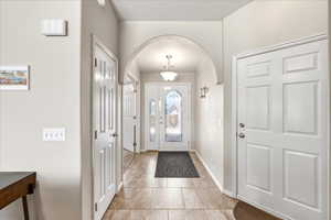 Entryway with arched walkways and light tile patterned floors