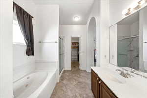 Bathroom featuring vanity, a tub with jets, a spacious closet, and a shower stall