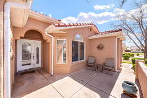 View of exterior entry with stucco siding, a patio, and a tiled roof