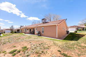 Back of property with a patio area, a tiled roof, stucco siding, a lawn, and a chimney
