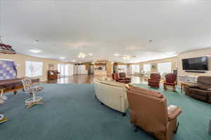 Carpeted living room with a ceiling fan