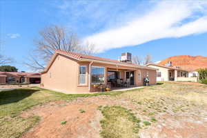 Back of property with a patio area, a yard, and stucco siding