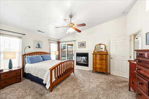 Bedroom with access to exterior, vaulted ceiling, ceiling fan, carpet, and a tile fireplace