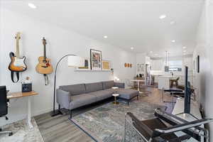Living room with light wood-type flooring, a desk, and recessed lighting