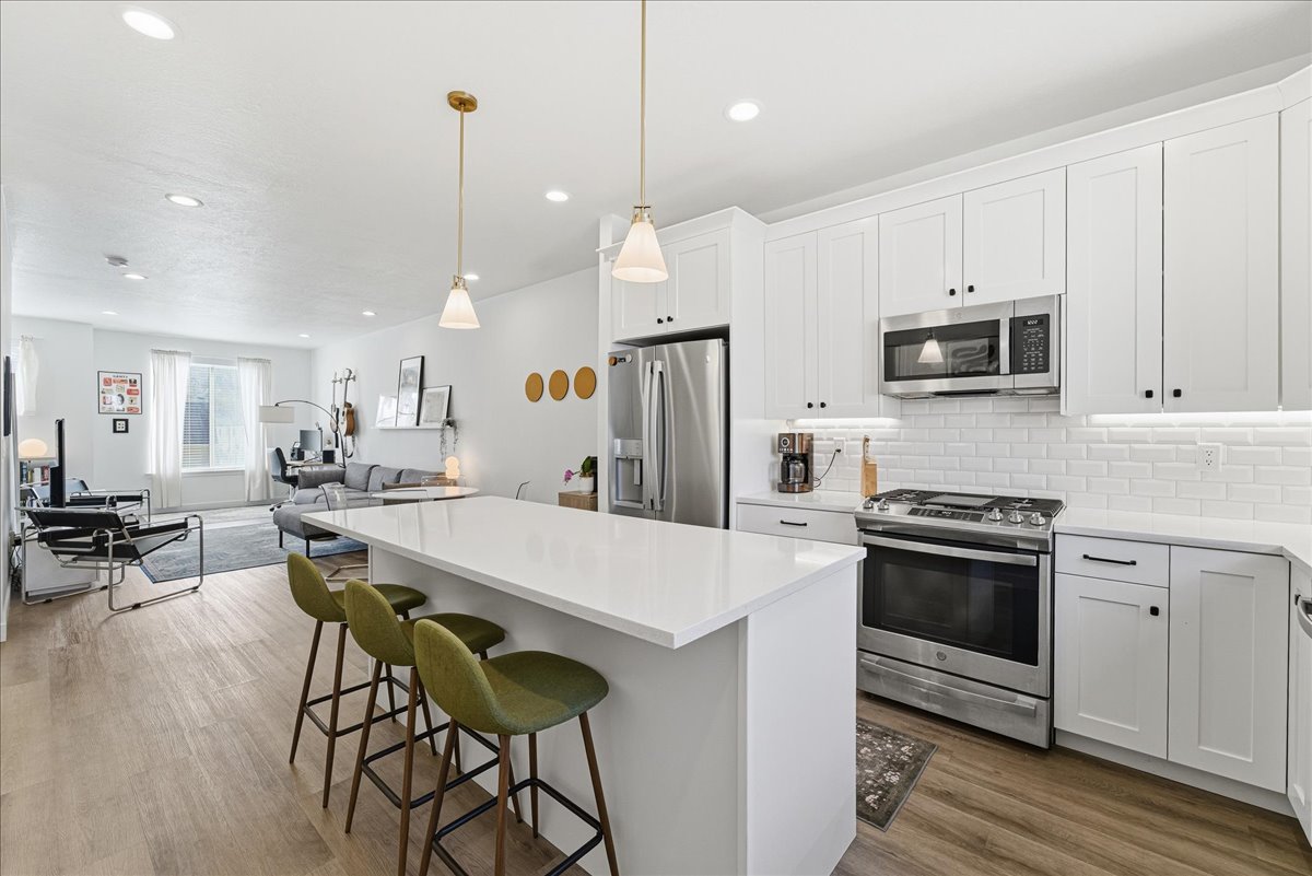 Kitchen with stainless steel appliances, white cabinetry, a kitchen breakfast bar, open floor plan, and a center island