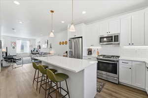 Kitchen with stainless steel appliances, white cabinetry, a kitchen breakfast bar, open floor plan, and a center island