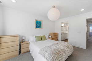 Carpeted bedroom with recessed lighting and ensuite bathroom