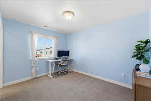 Home office with baseboards and light colored carpet