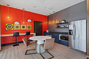 Kitchen featuring stainless steel appliances, open shelves, dark stone counters, and decorative light fixtures