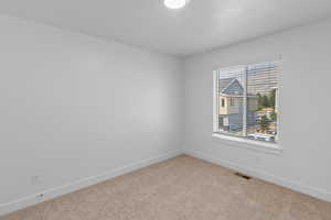 Carpeted spare room featuring baseboards