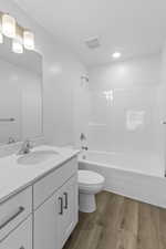 Bathroom featuring dark wood-style flooring, vanity, and shower / bath combination
