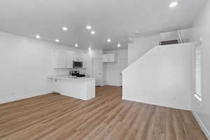 Kitchen with white cabinetry, a peninsula, light countertops, open floor plan, and recessed lighting