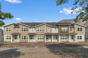 View of front of home featuring stone siding, roof with shingles, and board and batten siding