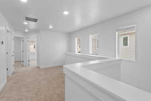 Hall with recessed lighting, an upstairs landing, and light carpet
