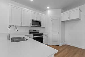 Kitchen featuring range with gas stovetop, light stone countertops, stainless steel microwave, white cabinets, and recessed lighting