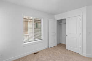 Unfurnished bedroom with a closet and light colored carpet