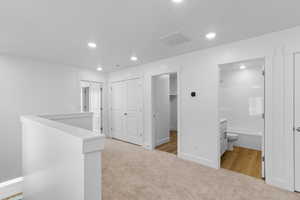 Hallway featuring light carpet, an upstairs landing, and recessed lighting